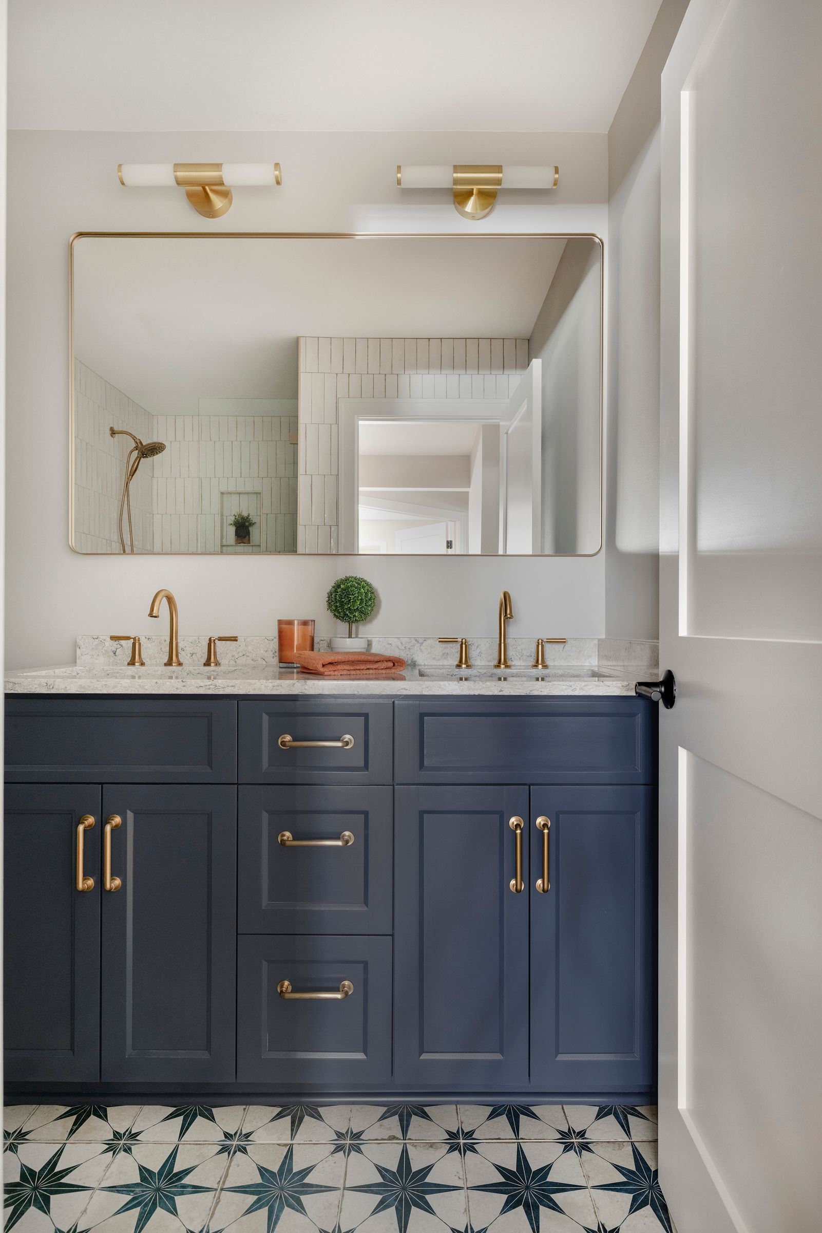 Navy vanity with gold fixtures and star-pattern tile in a bright, modern bathroom