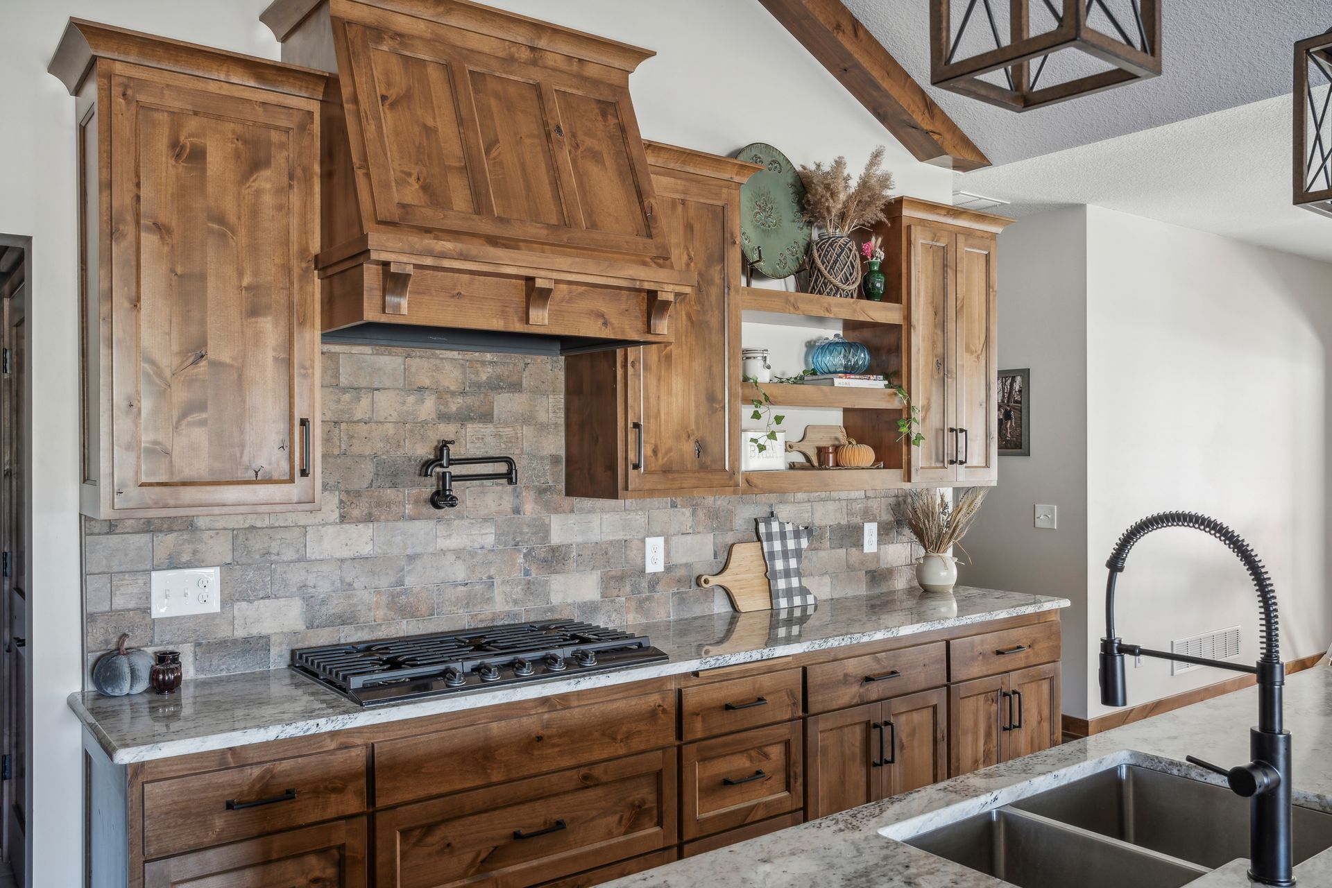 Rustic kitchen with wood cabinets, stone backsplash, gas range, and farmhouse sink