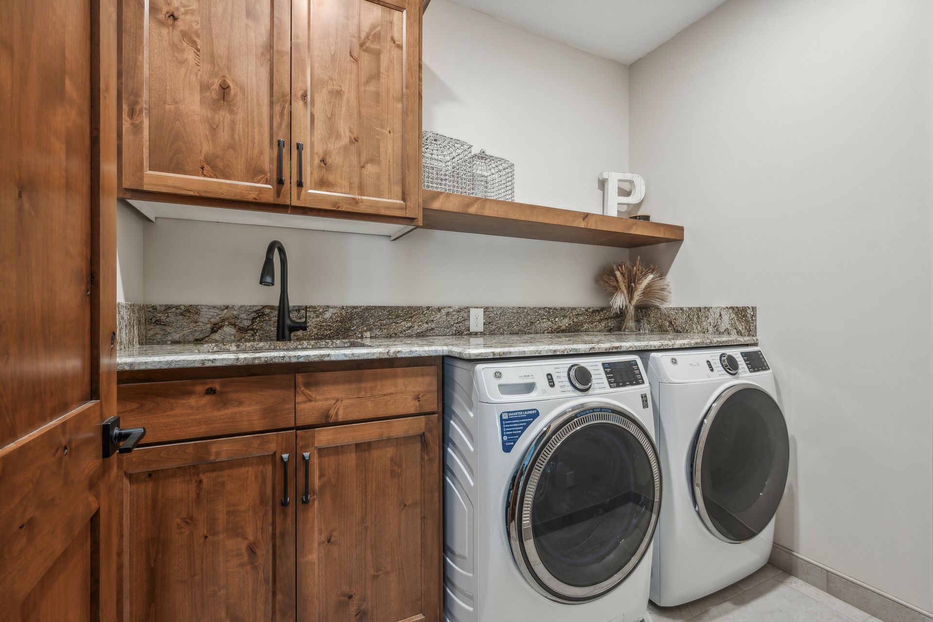 Laundry room with wood cabinets, sink, countertop, and side-by-side washer and dryer
