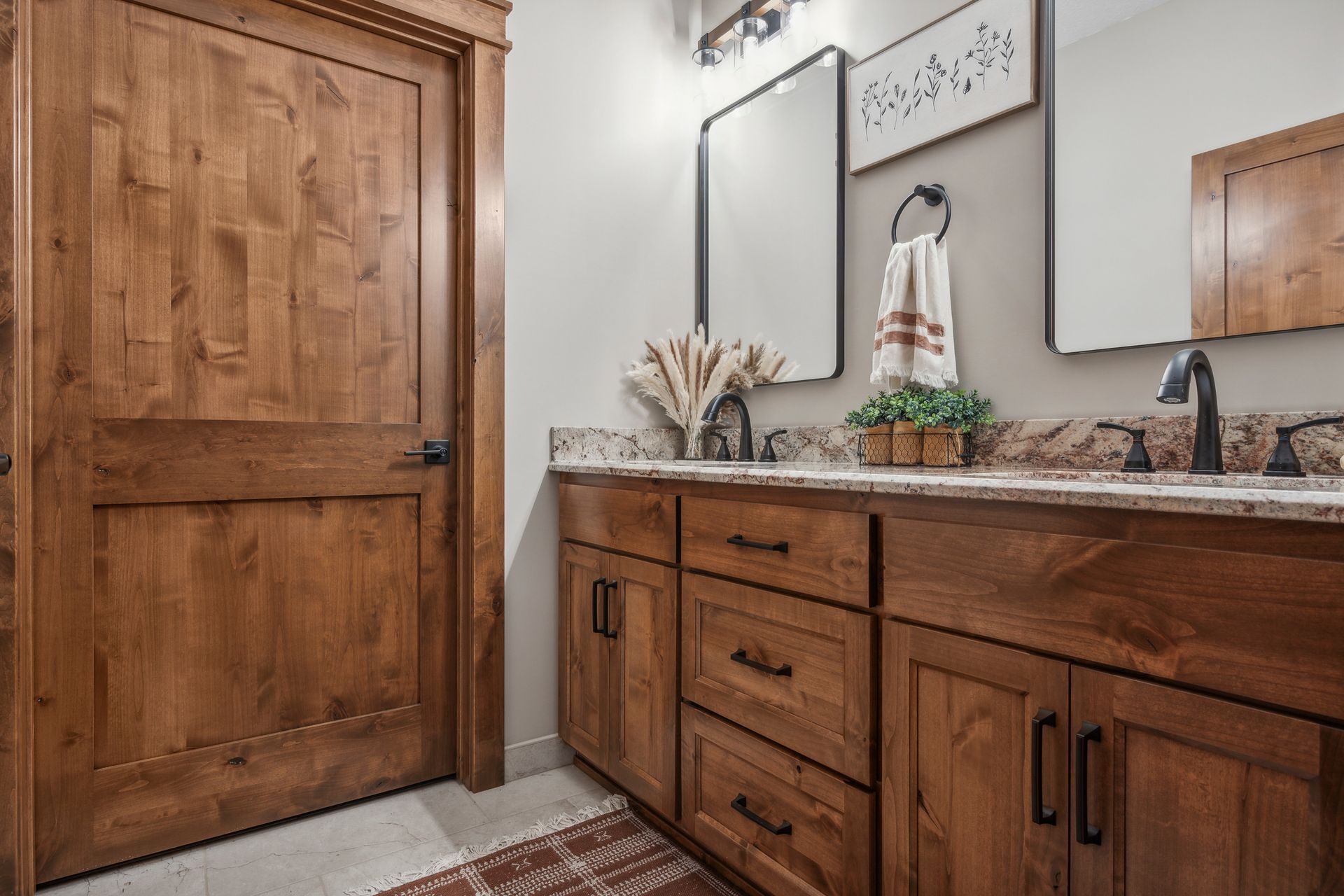 Bathroom vanity with wood cabinets, granite countertop, mirror, and wooden door