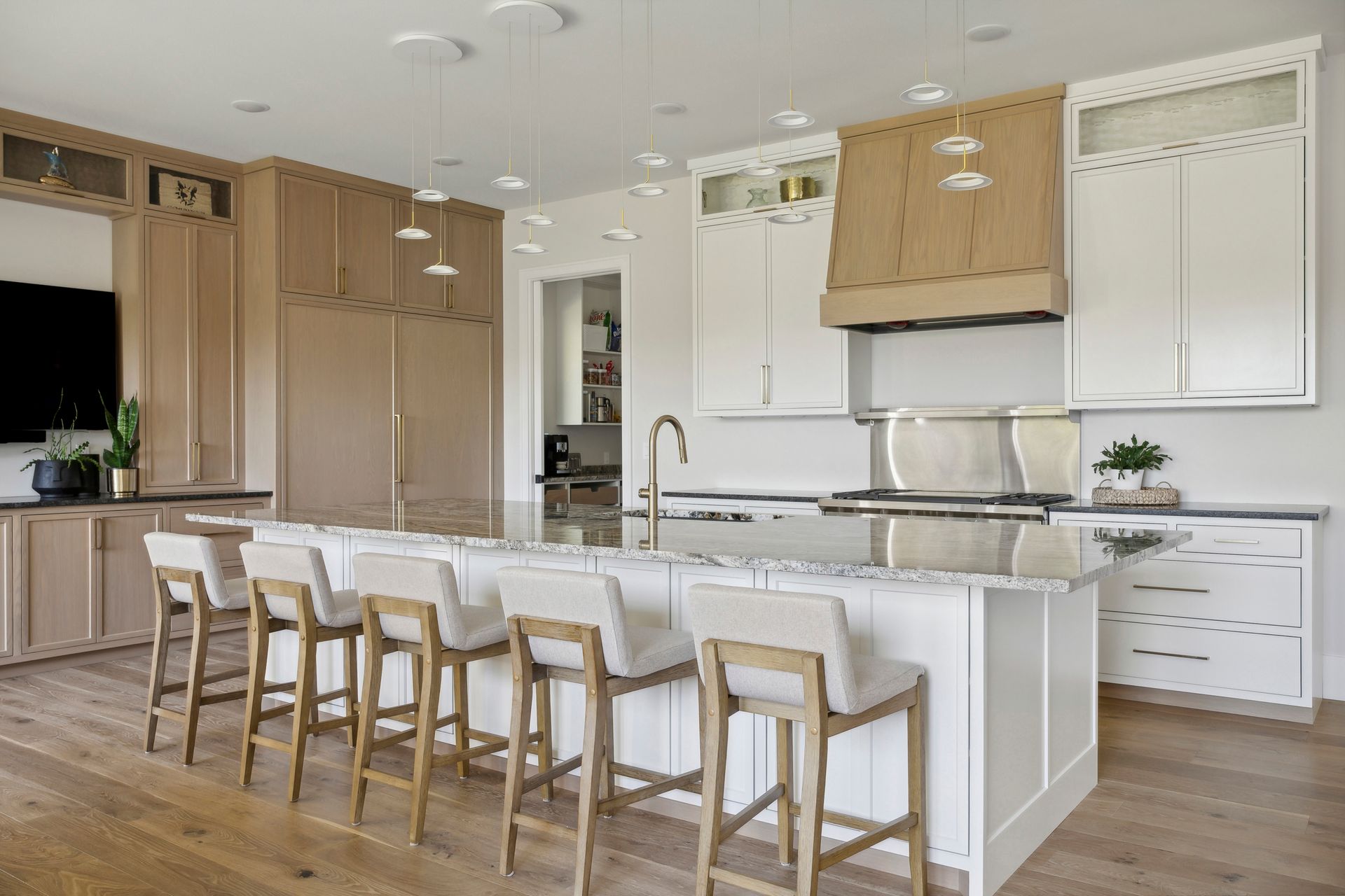 Modern white kitchen with wood accents, island seating, and stainless steel appliances