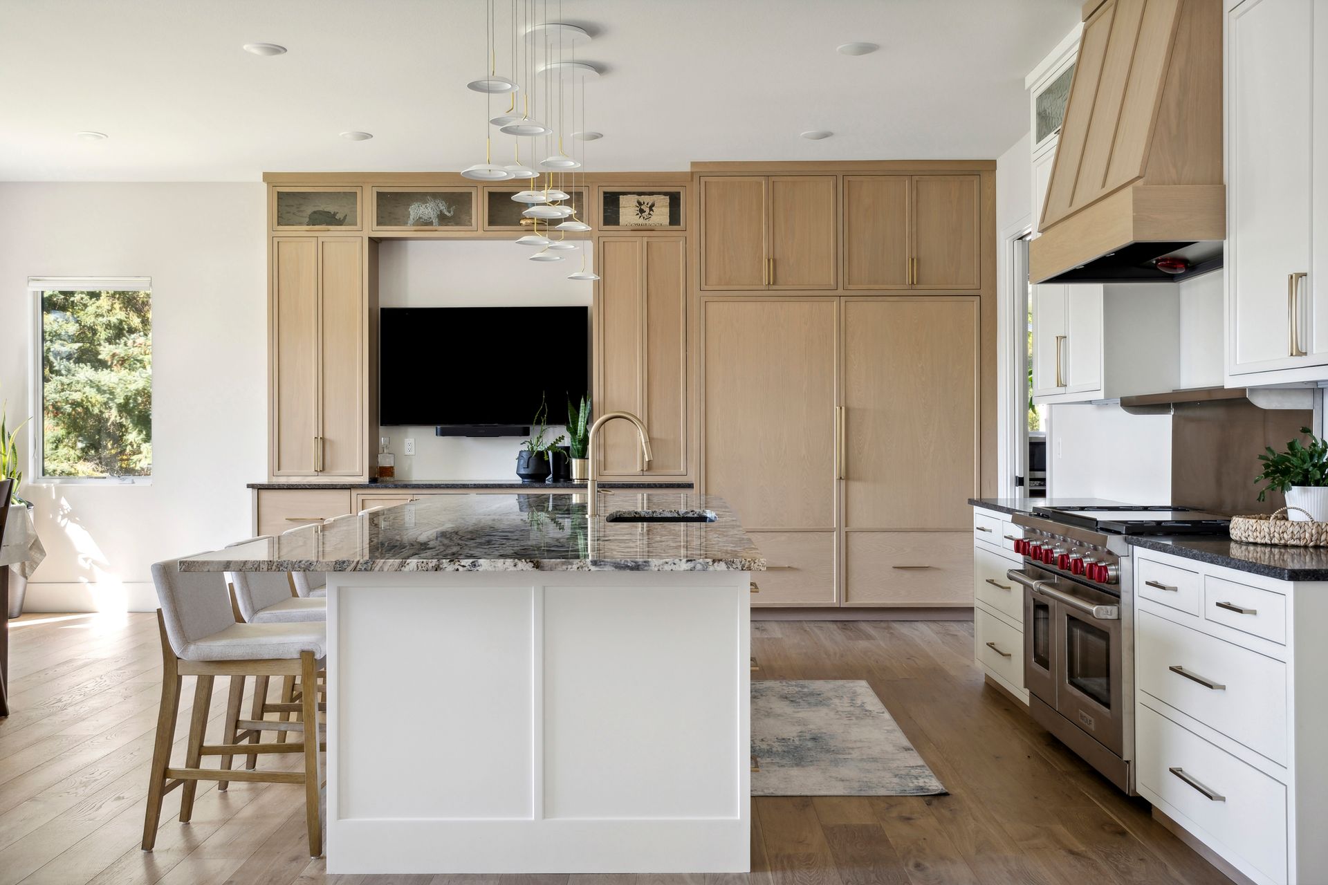 Bright modern kitchen with white island, wood cabinets, stainless range, and open dining area