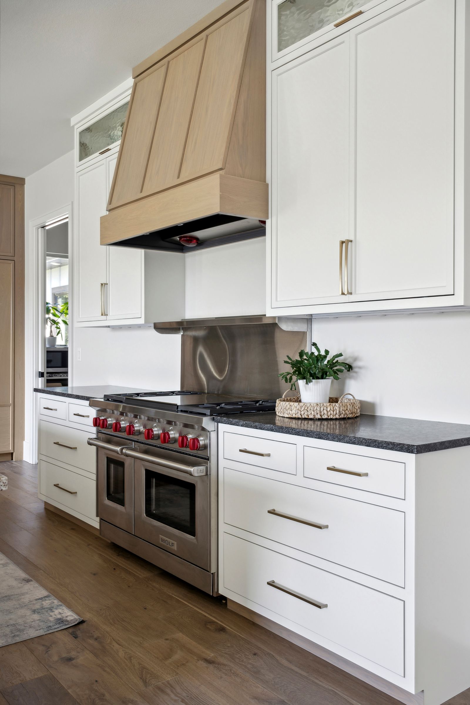 Modern kitchen with white cabinets, dark countertops, stainless range, and wood floors