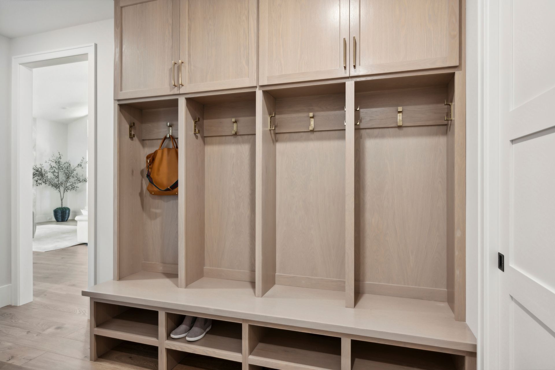 Modern mudroom bench with light wood lockers, hooks, and cubbies in a bright entryway