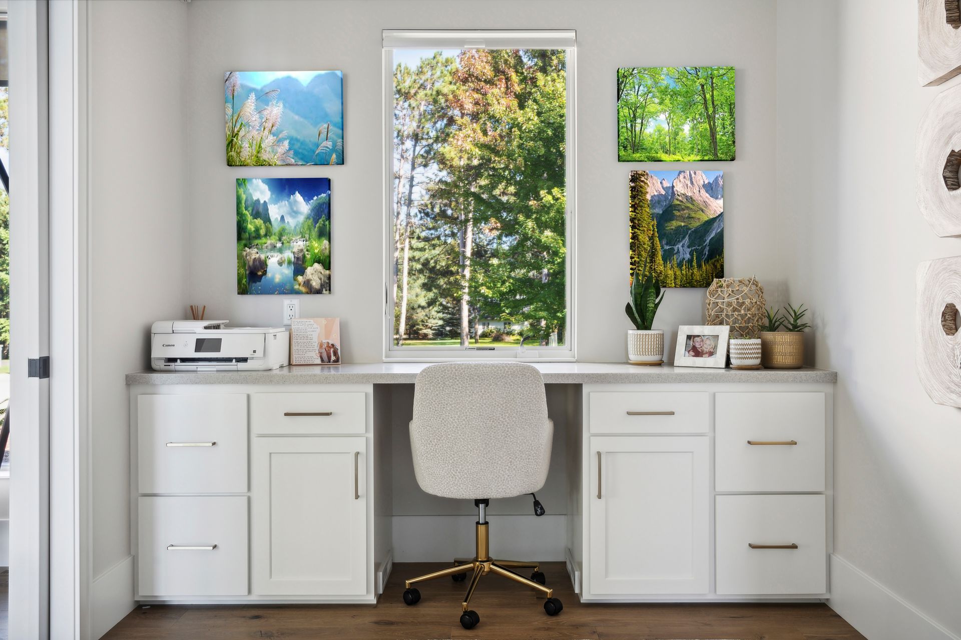 Bright white home office with desk, chair, plants, and colorful landscape art above the window