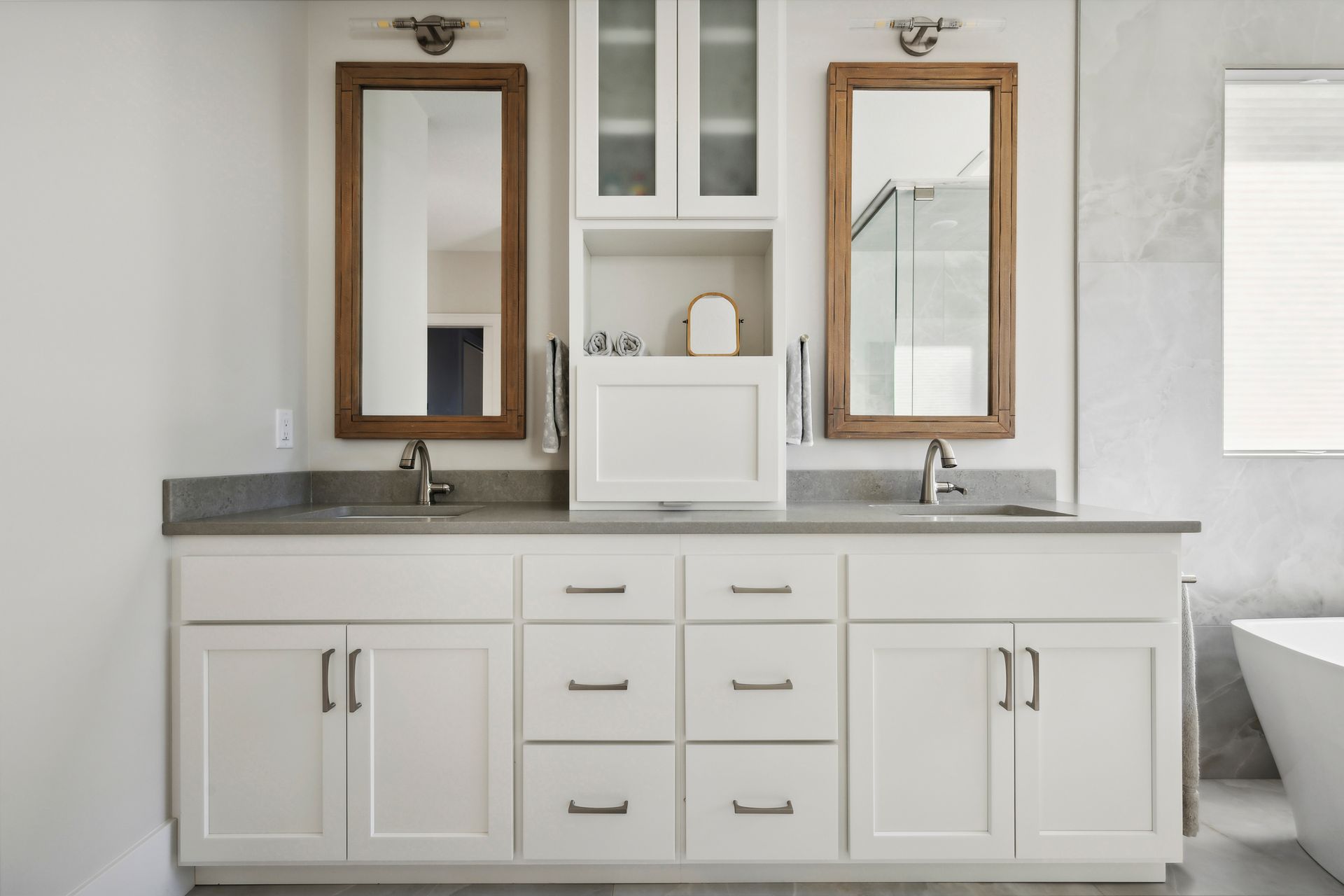 Modern white bathroom vanity with double mirrors, gray countertop, and built-in storage cabinets