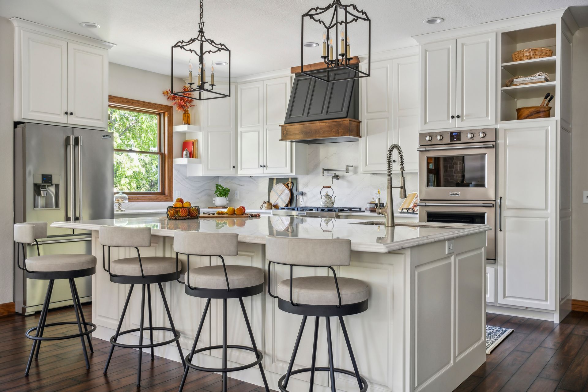 Bright white kitchen with island, black bar stools, and stainless steel appliances