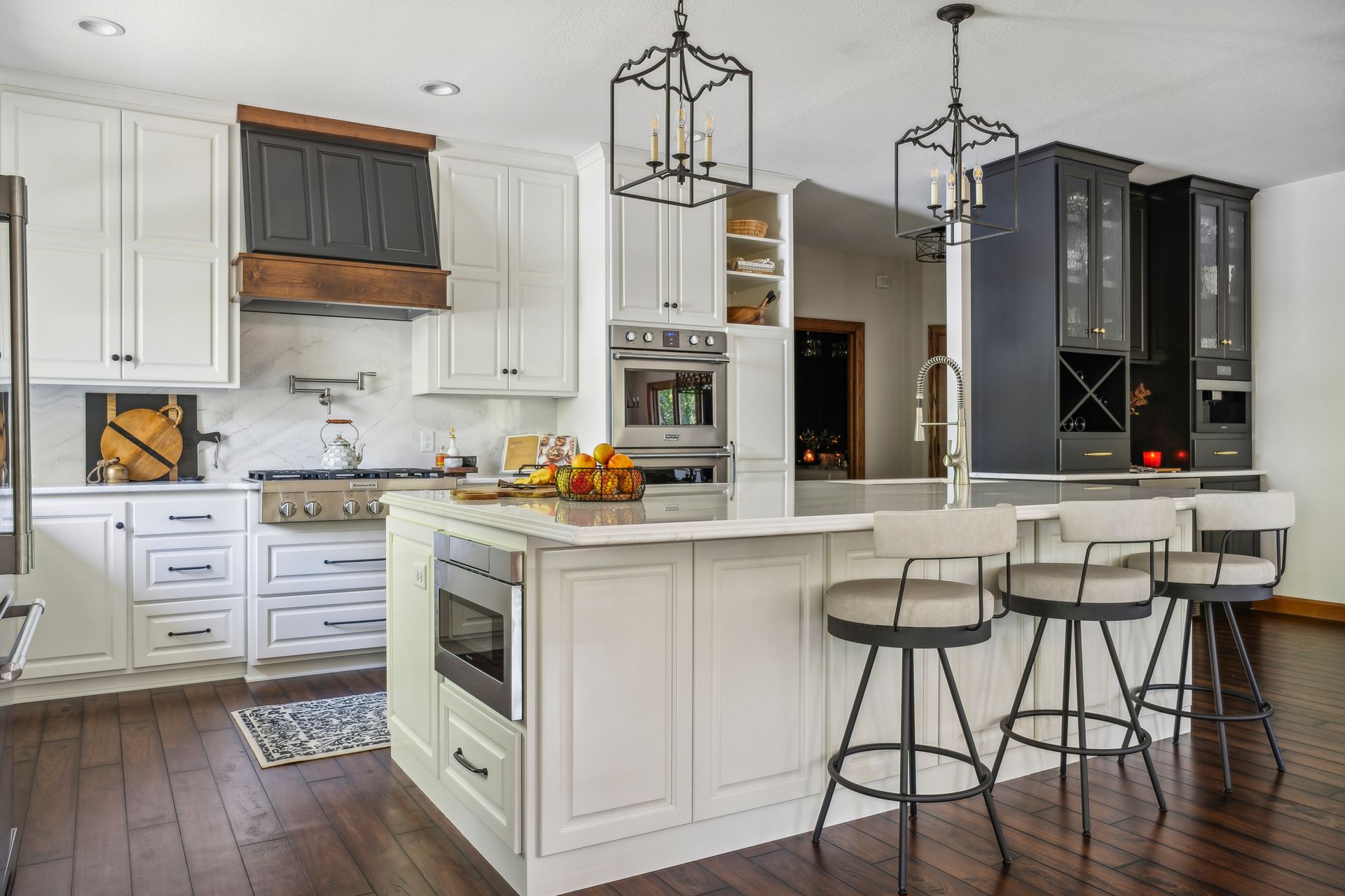 Bright modern kitchen with white cabinets, dark island, and two bar stools