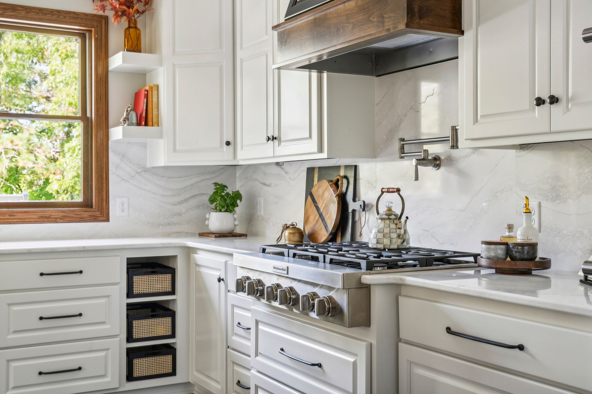 Bright white kitchen with gas stove, window, and potted herbs on the counter