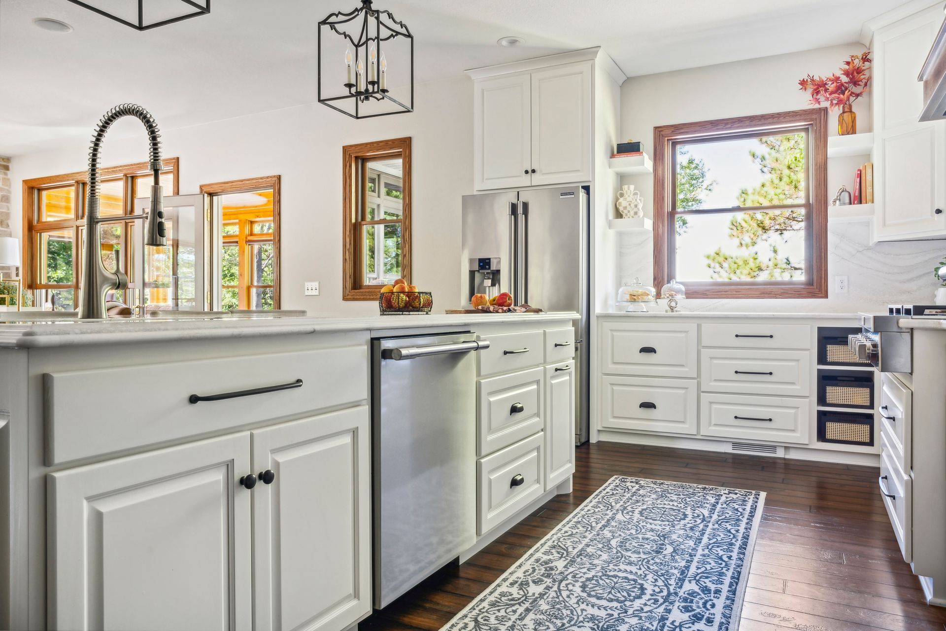 Bright white kitchen with island, farmhouse sink, wood floors, and a window over the counter