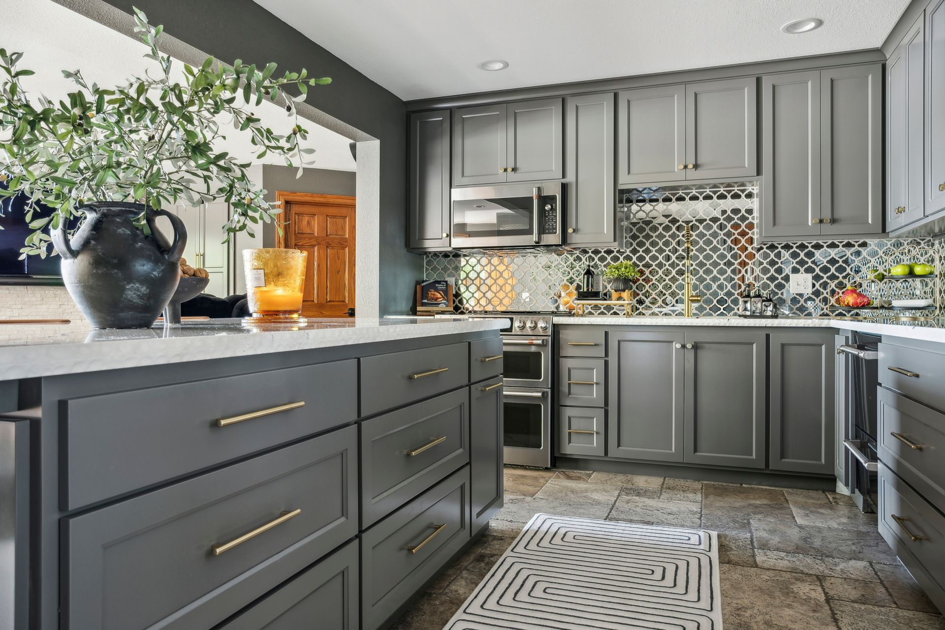 Modern gray kitchen with mosaic backsplash, island, and potted plant by the window