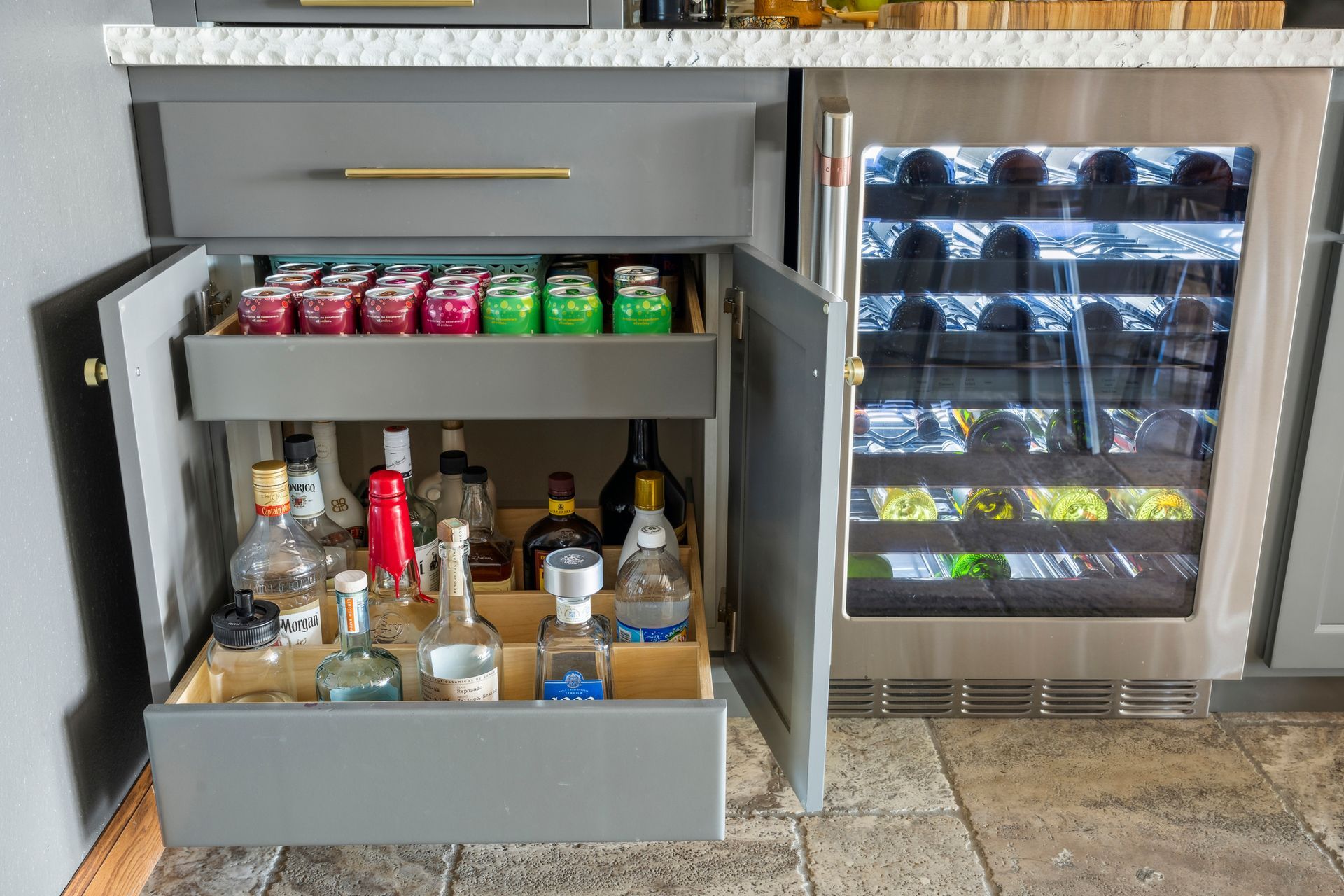 Open liquor cabinet with bottles and wine, beside a small refrigerated drink display
