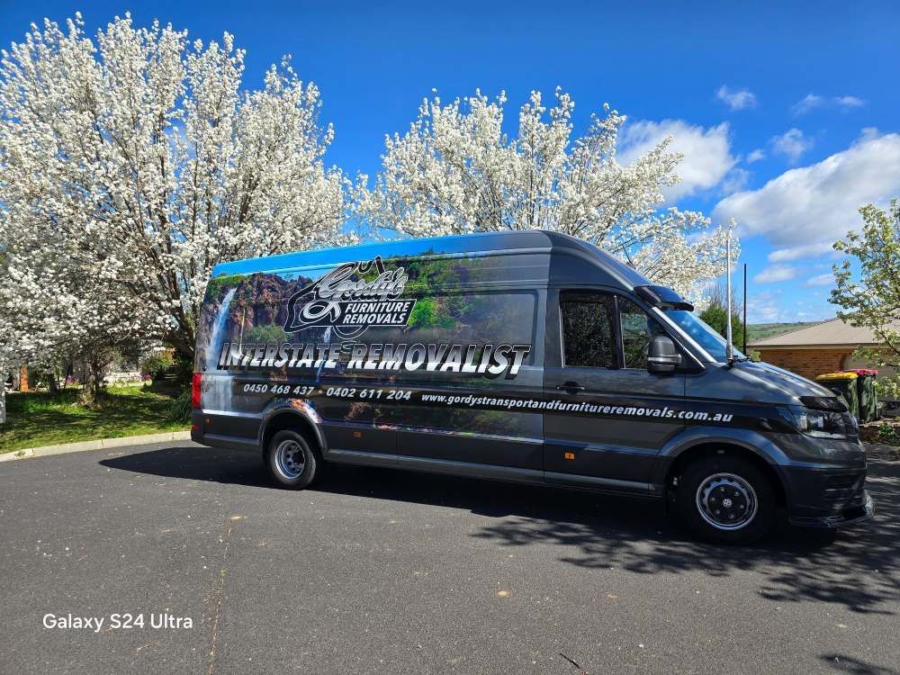 A Van is Parked on the Side of the Road in Front of a Tree — Gordy's Furniture Removals in Bathurst, NSW