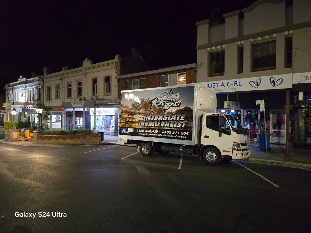 Small Delivery Truck With Signage in a Parking Lot at Night — Gordy's Furniture Removals in Bathurst, NSW