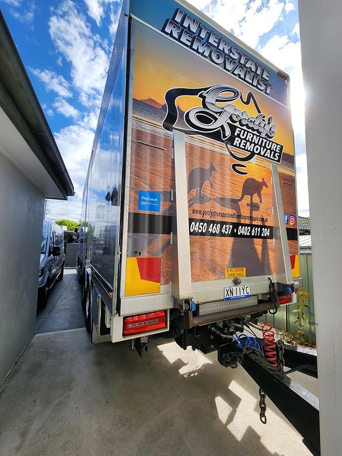 A Large Moving Truck Is Parked In Front Of A House — Gordy's Furniture Removals in Bathurst, NSW