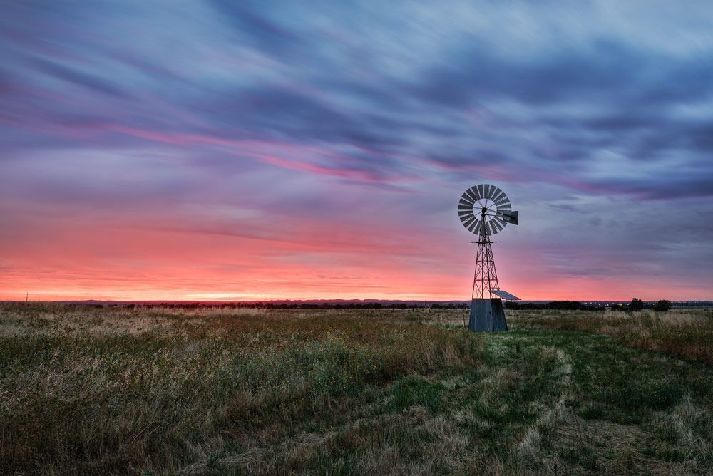 A Windmill Is Sitting In The Middle Of A Field At Sunset — Gordy's Furniture Removals in Bathurst, NSW