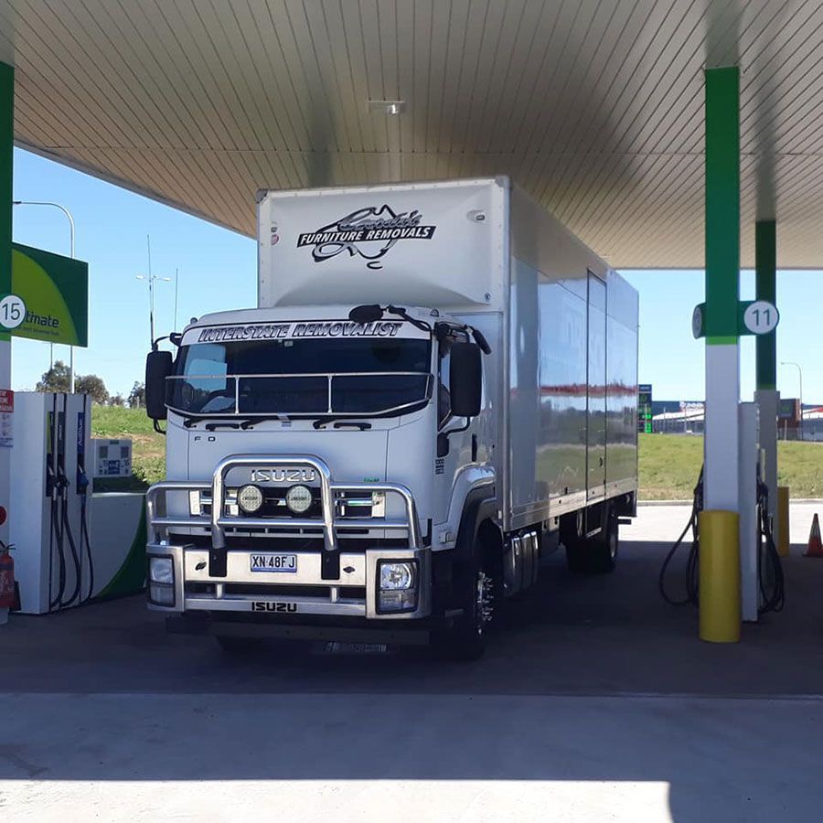 A Large White Truck Is Parked At A Gas Station — Gordy's Furniture Removals in Bathurst, NSW