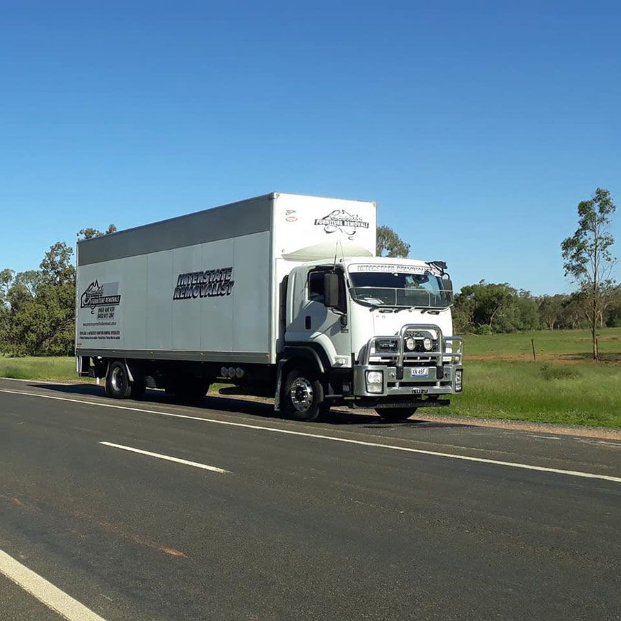 A Large White Truck Is Driving Down A Road — Gordy's Furniture Removals in Bathurst, NSW