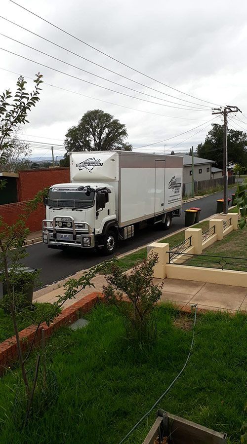A White Moving Truck Is Parked On The Side Of The Road — Gordy's Furniture Removals in Bathurst, NSW