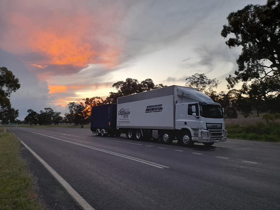 A White Truck Is Driving Down A Road At Sunset — Gordy's Furniture Removals in Bathurst, NSW