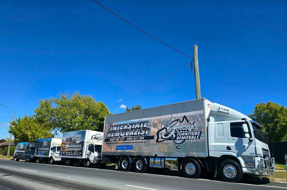 A Row of Trucks Are Parked on the Side of a Road — Gordy's Furniture Removals in Bathurst, NSW