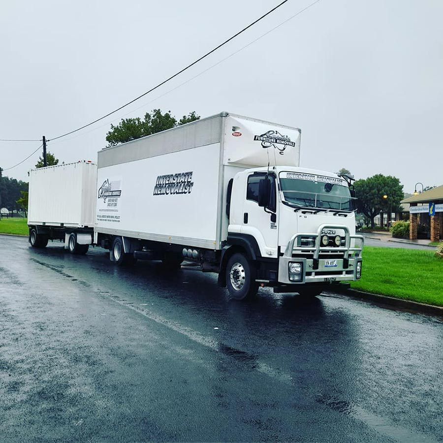 A White Truck Is Parked On The Side Of The Road Next To A Trailer — Gordy's Furniture Removals in Bathurst, NSW