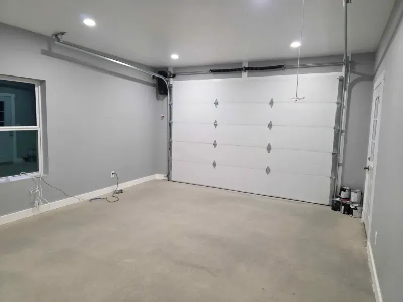 Empty garage with white walls, concrete floor, and a closed white sectional door