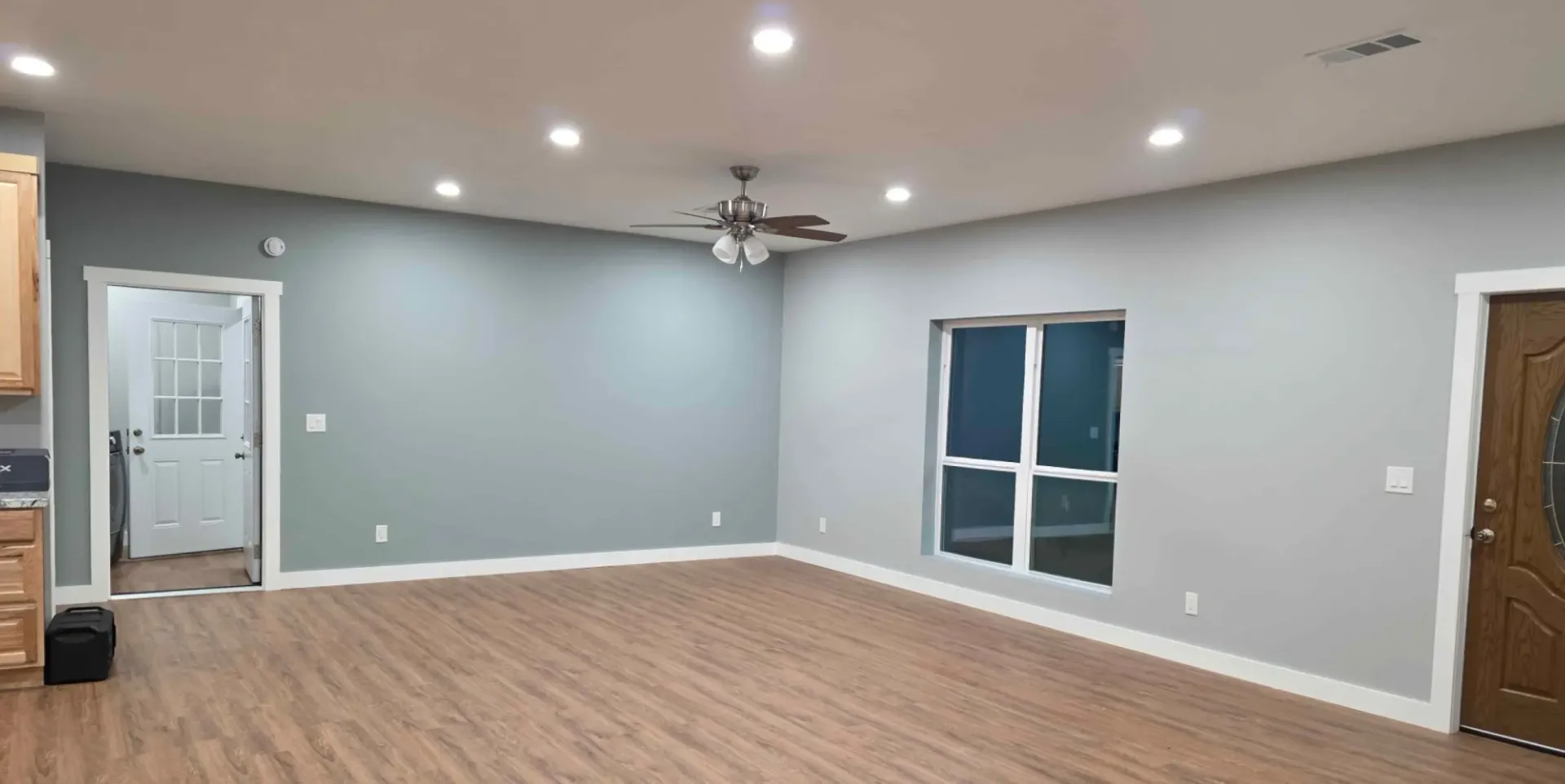 Empty gray living room with carpet, recessed lights, ceiling fan, and window curtains