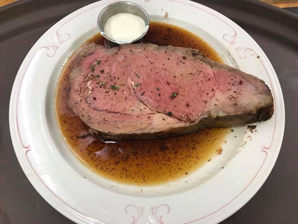Plate with a pink-centered steak in brown sauce, topped with pepper and a small dollop of cream