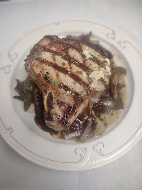 Grilled steak with dark sauce on a white plate with decorative rim