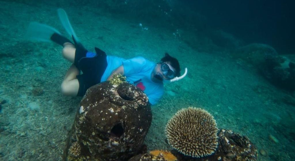A man is swimming in the ocean near a coral reef.