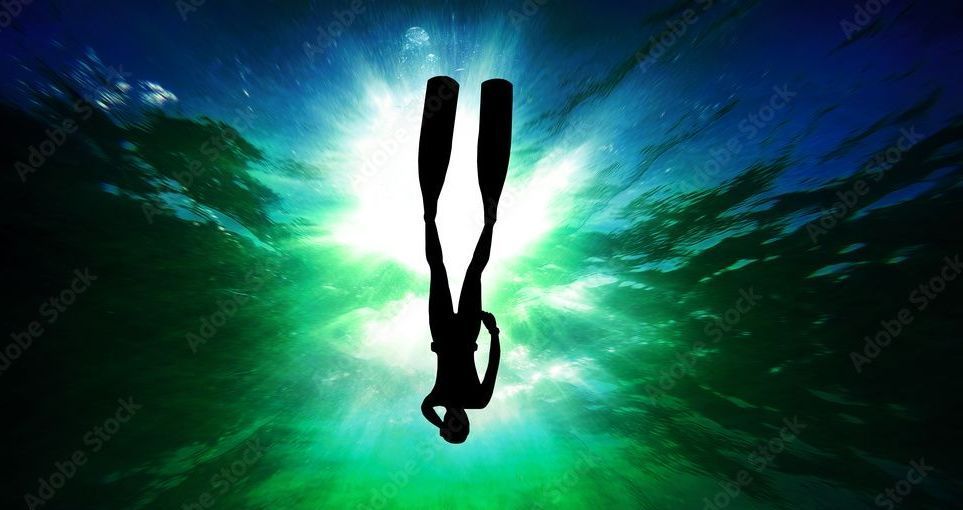 A silhouette of a scuba diver in the ocean.
