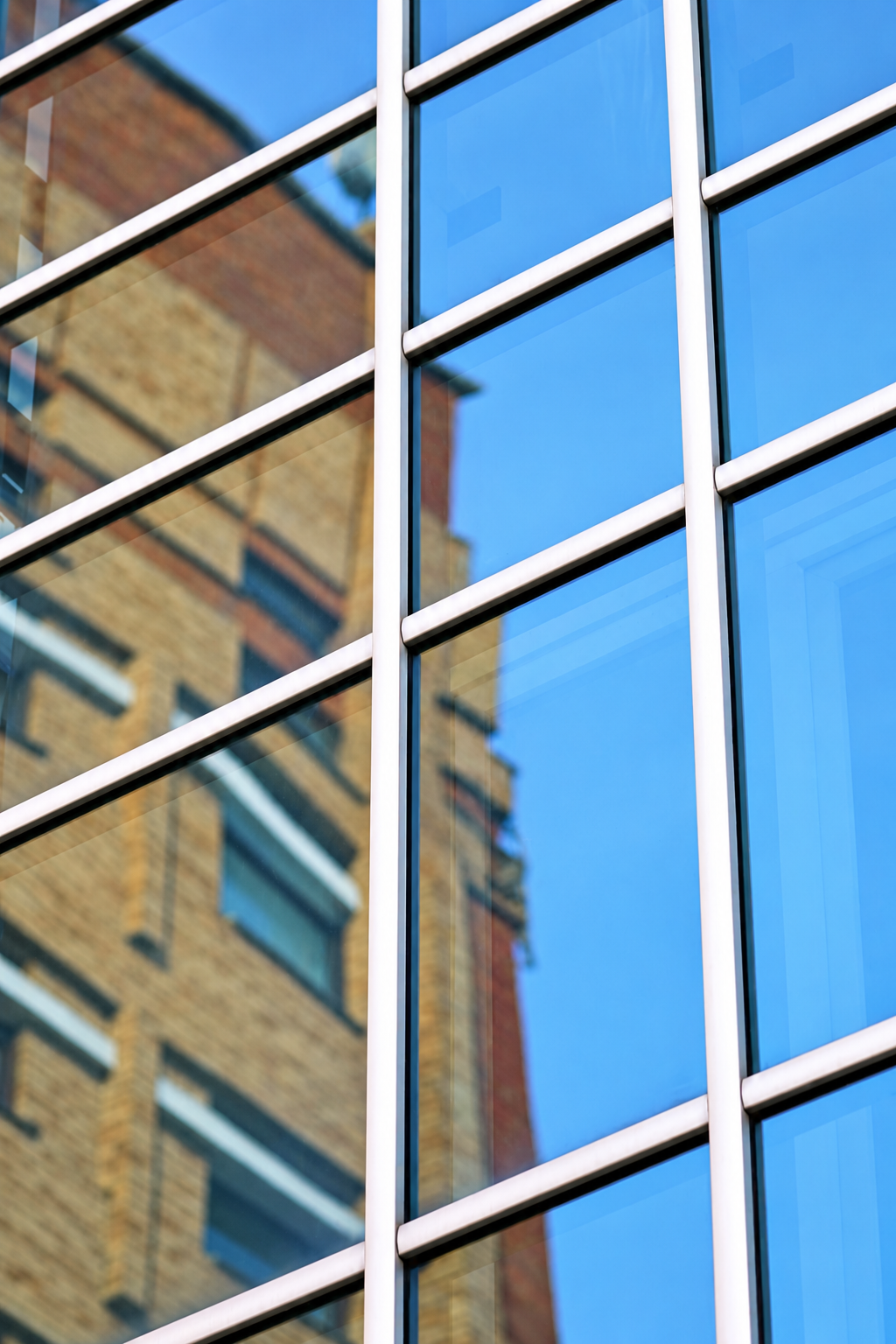 Reflection of a brick building in blue-tinted glass window panes