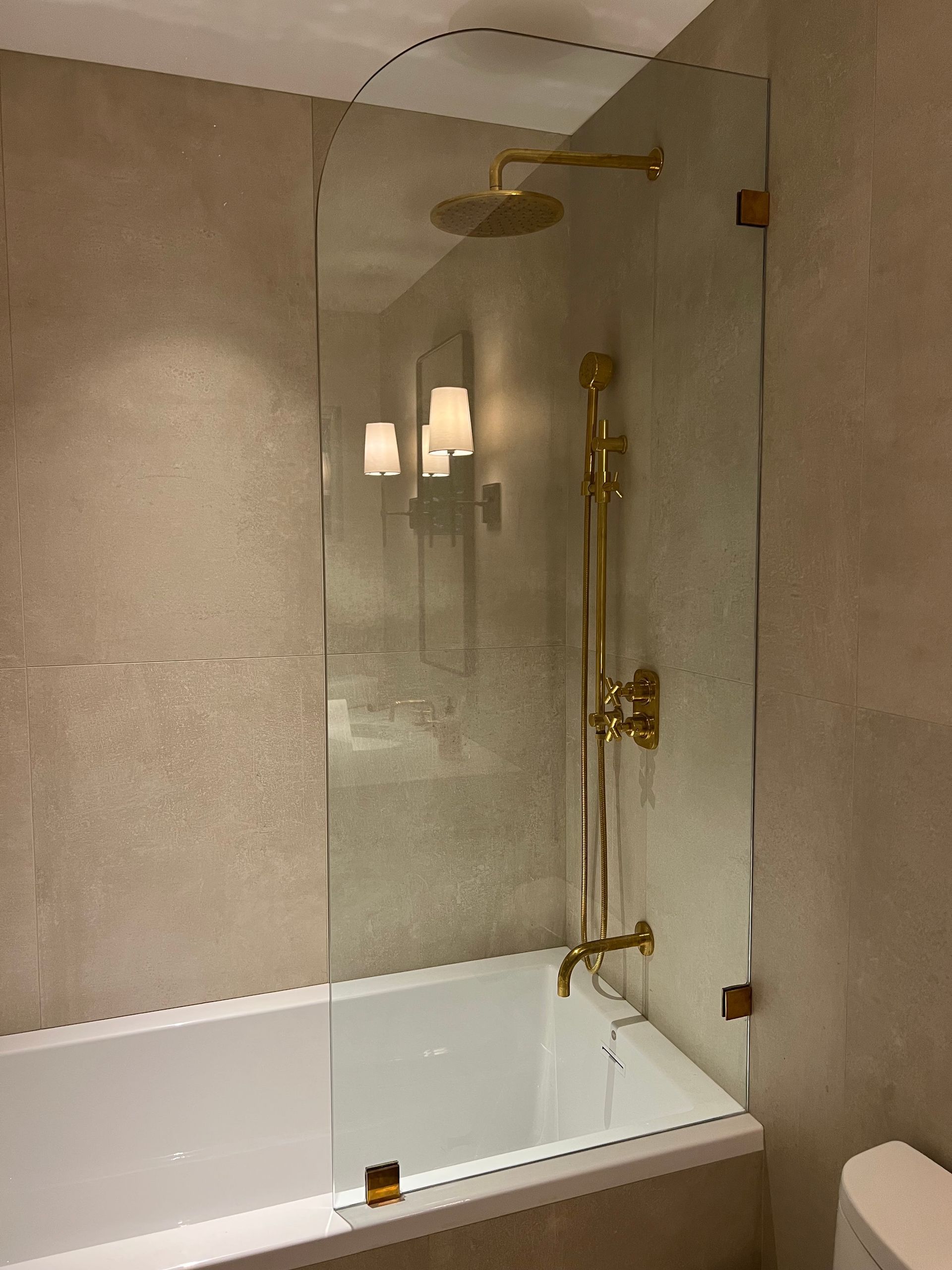 Modern bathroom with white tub, glass shower enclosure, and brass shower fixtures