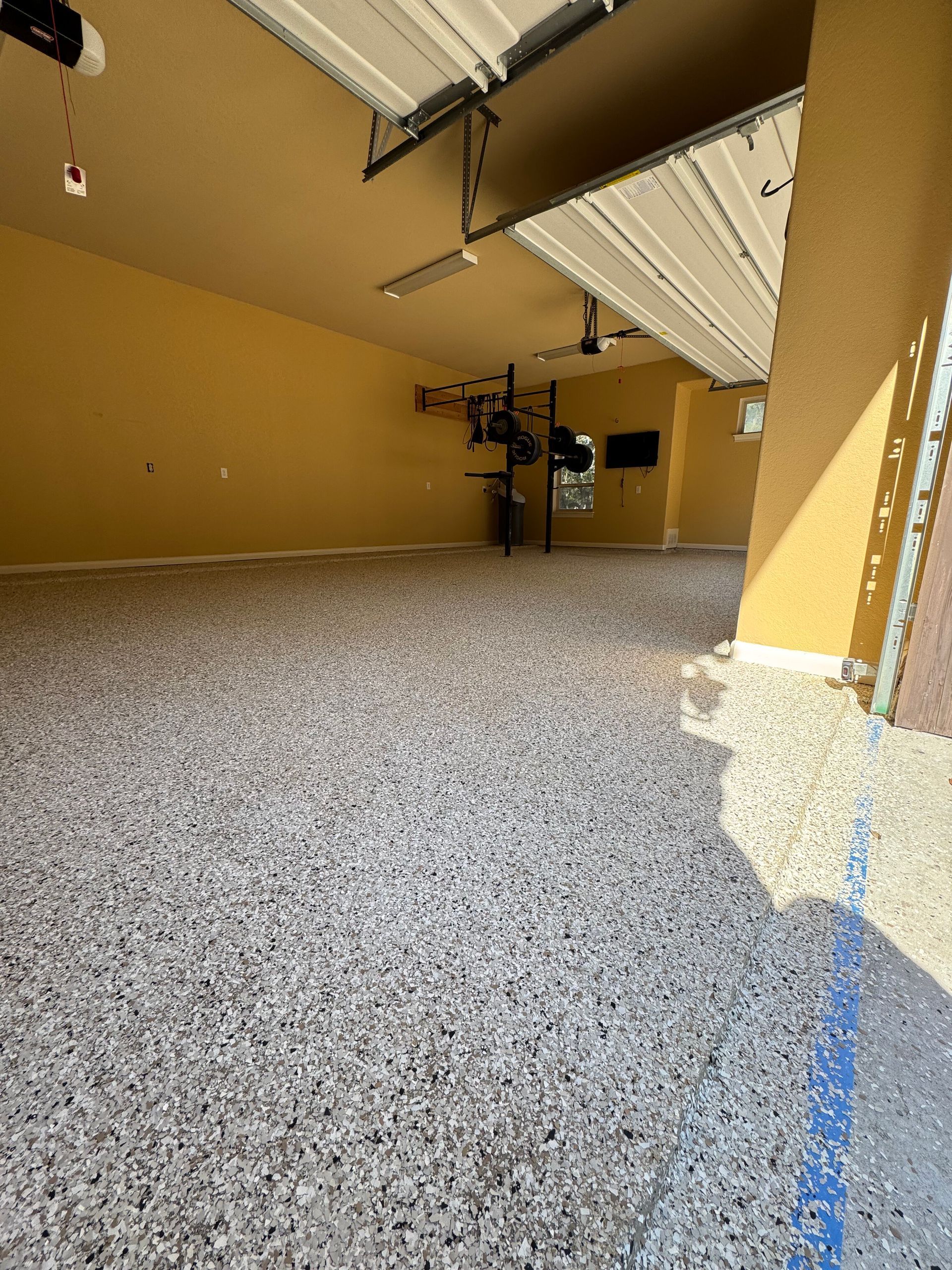 Empty covered patio with tan walls, speckled concrete floor, and a blue line marking on the ground.