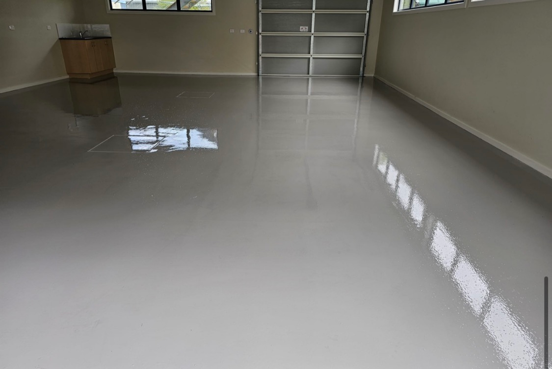 Empty room with glossy light-gray floor and reflections, beige walls, and a small staircase at the back.