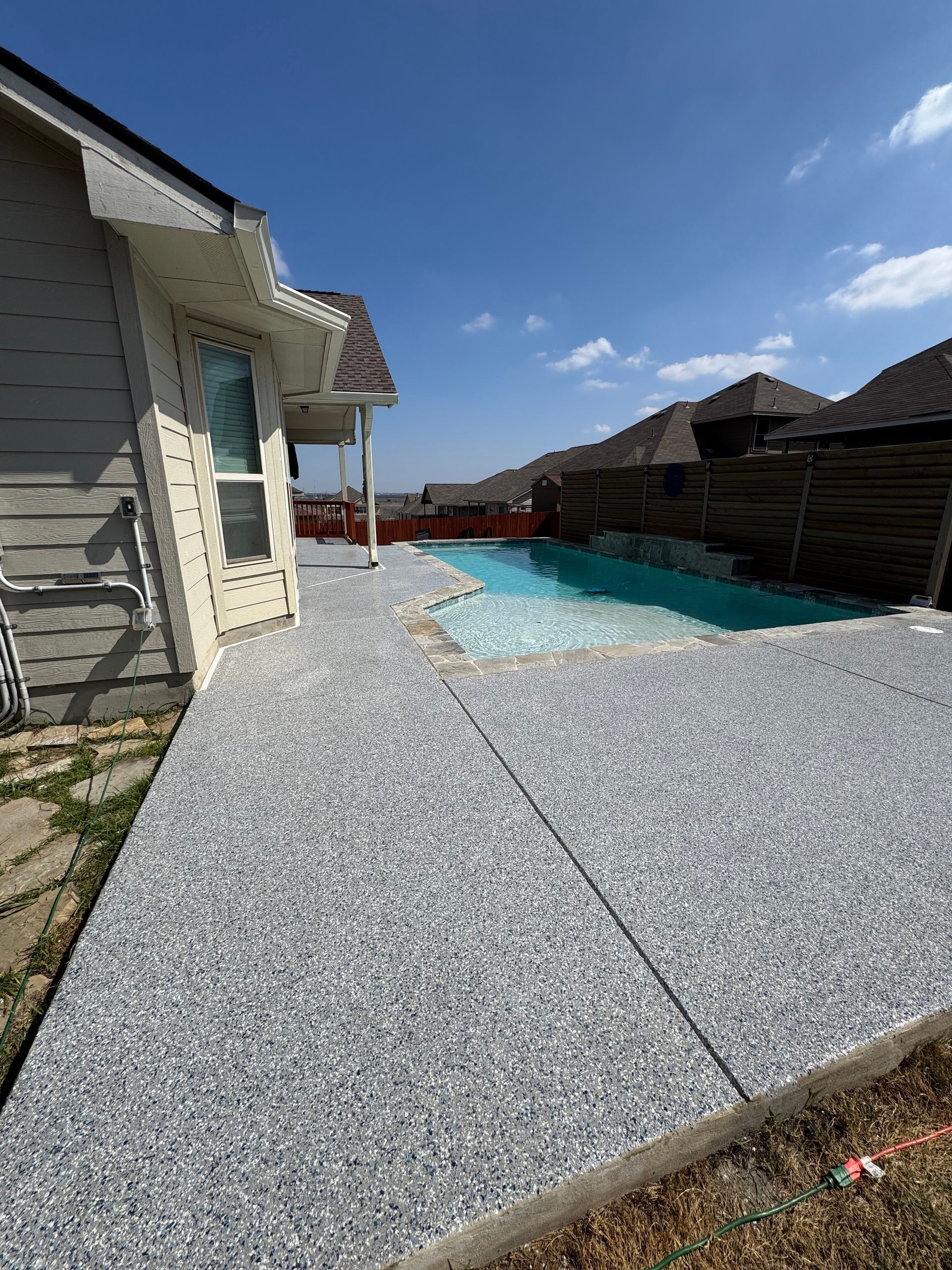 Backyard patio with a small swimming pool beside a house under a clear blue sky
