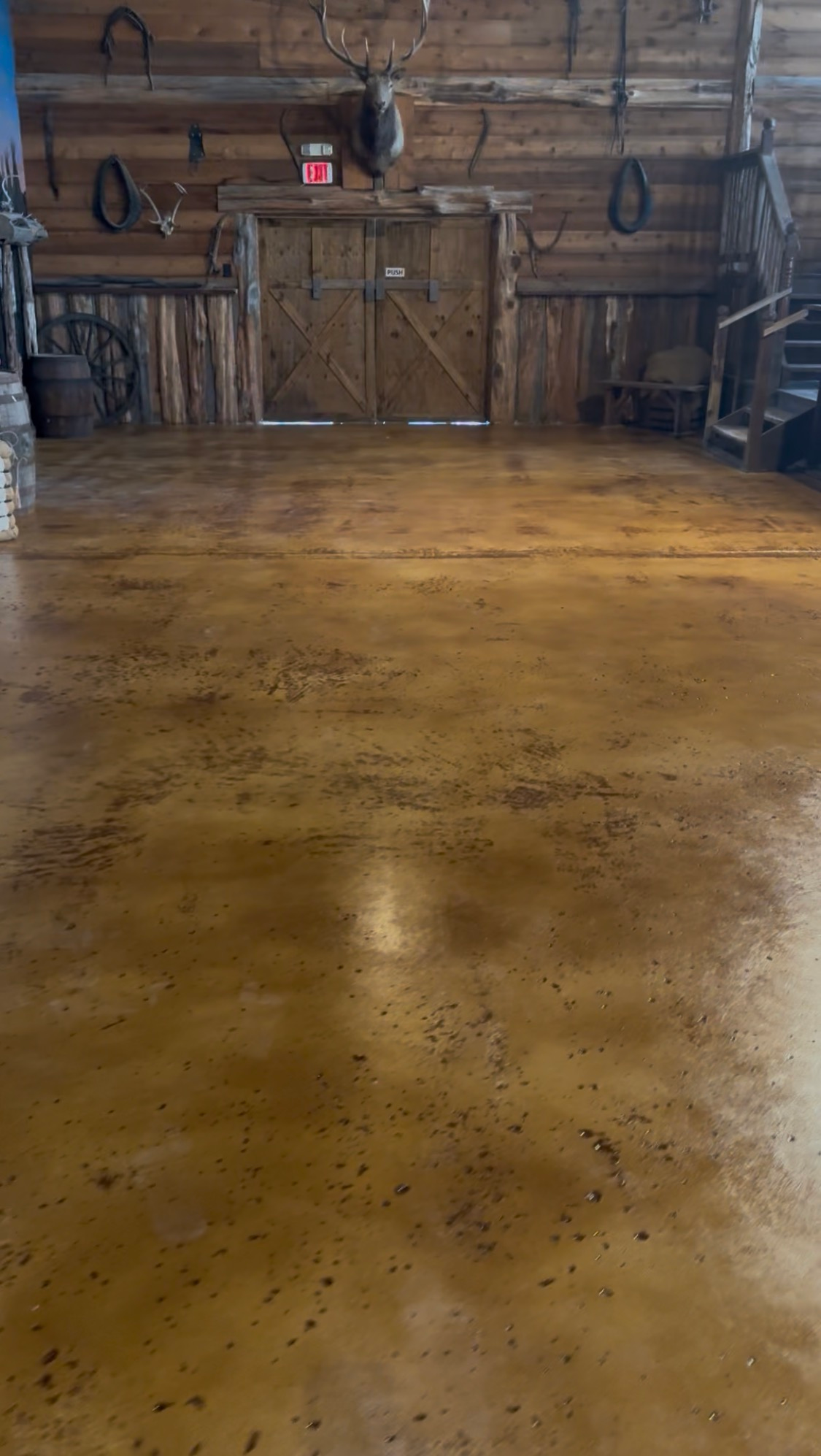 Wooden barn interior with a polished floor and rustic double doors on the far wall