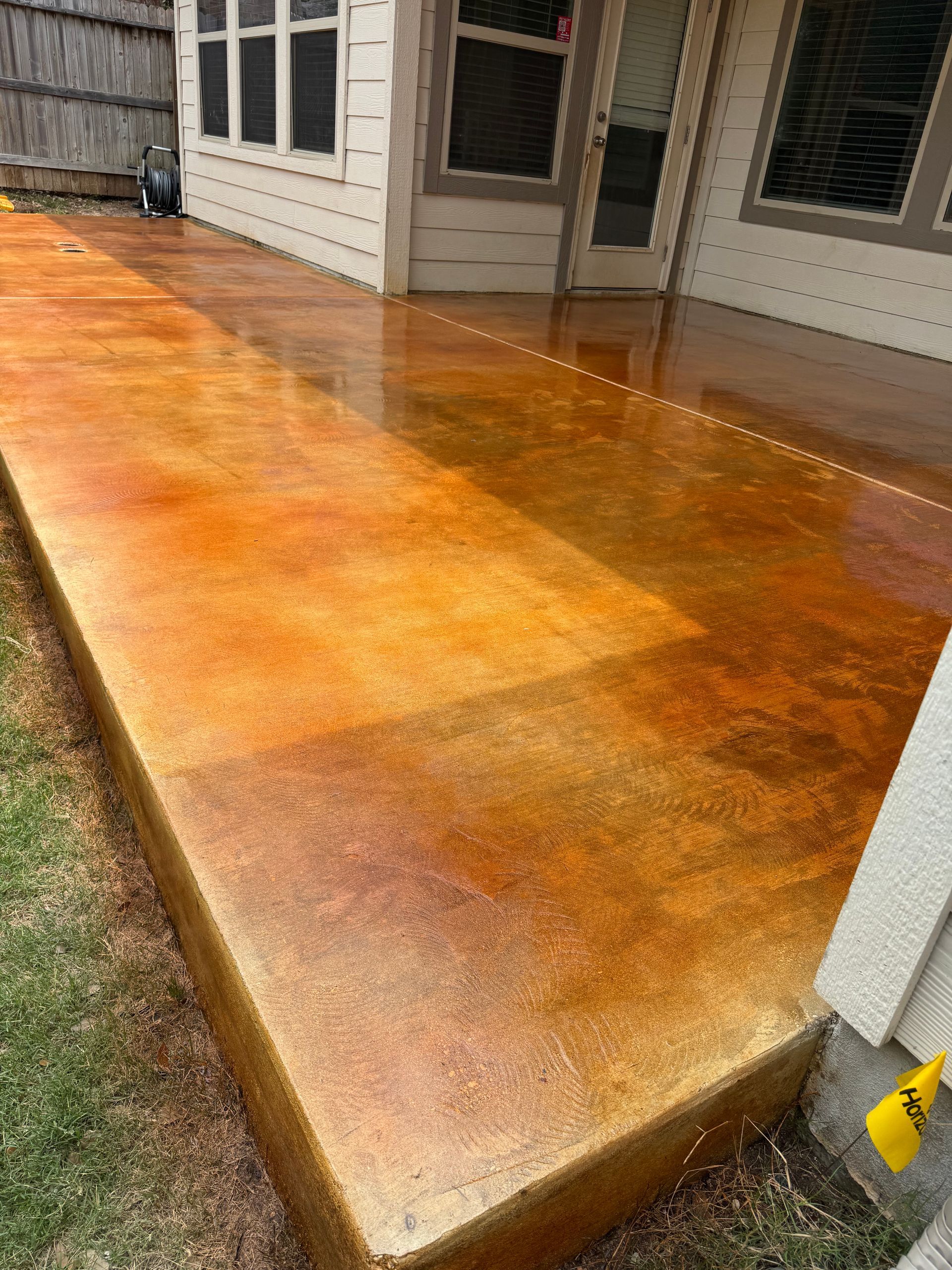 Freshly stained orange concrete patio beside a house exterior