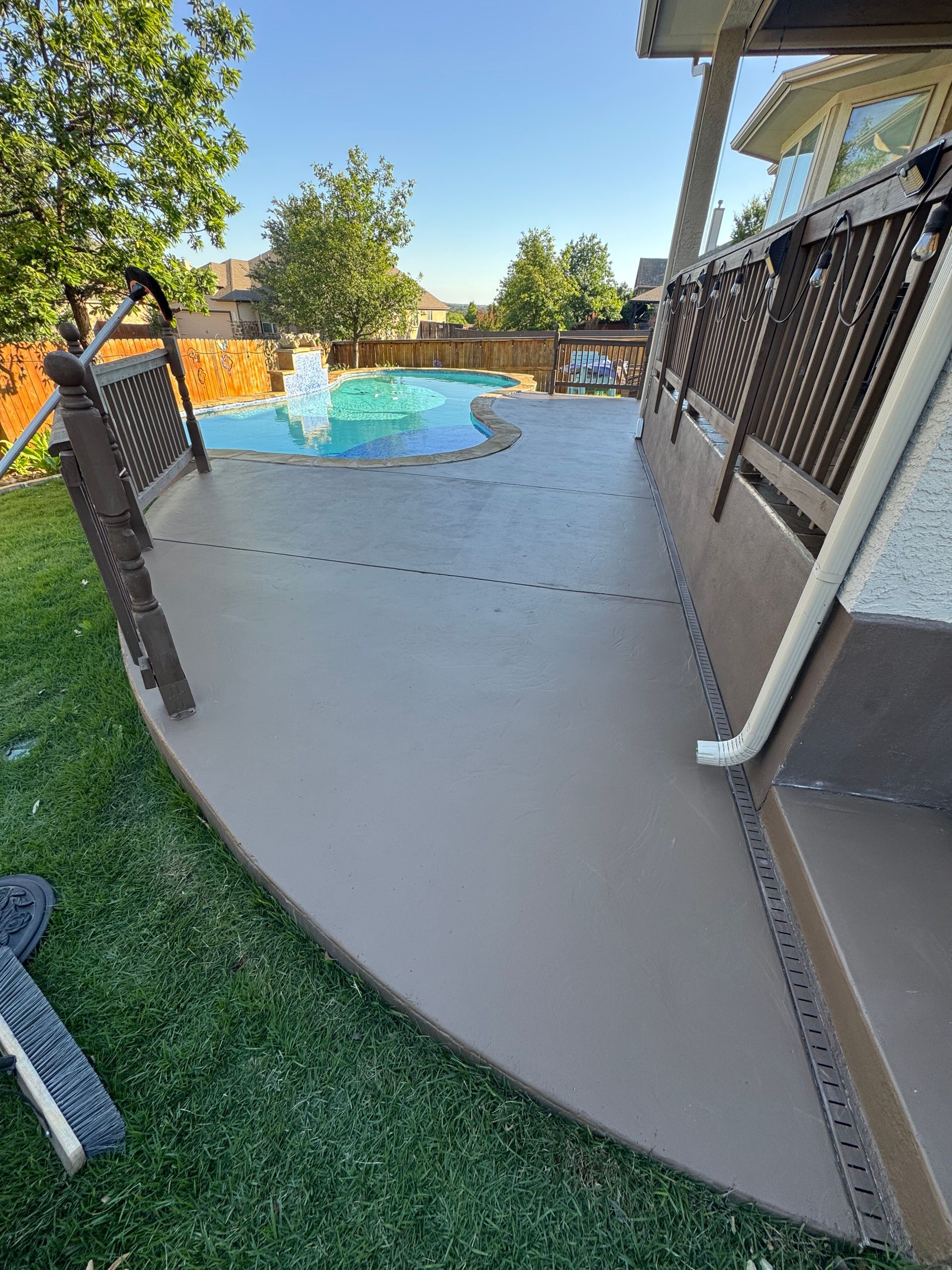 Poolside walkway with black railings and a turquoise swimming pool in a sunny backyard