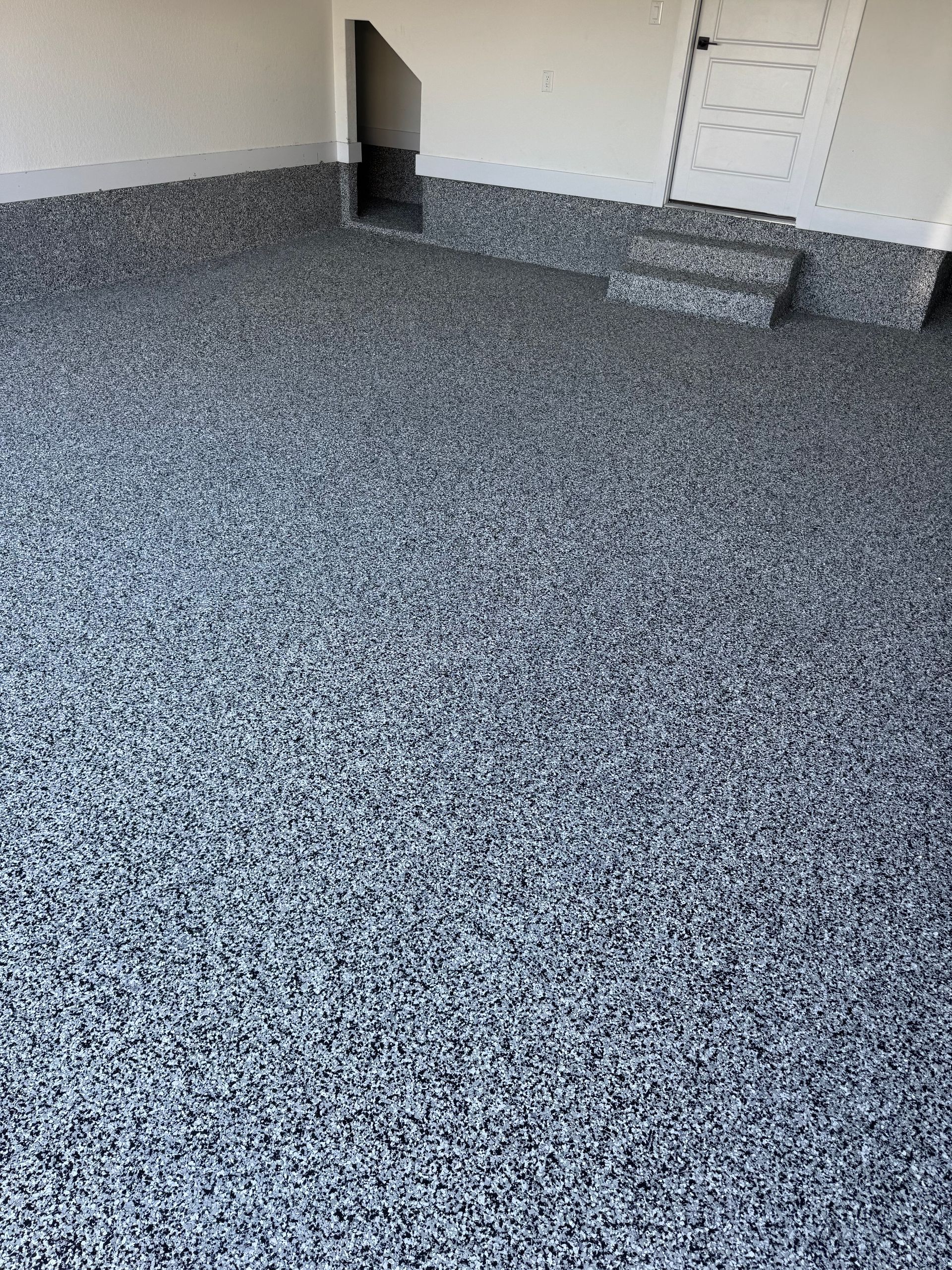Empty speckled gray room with carpet and a small black wall opening near a white doorway
