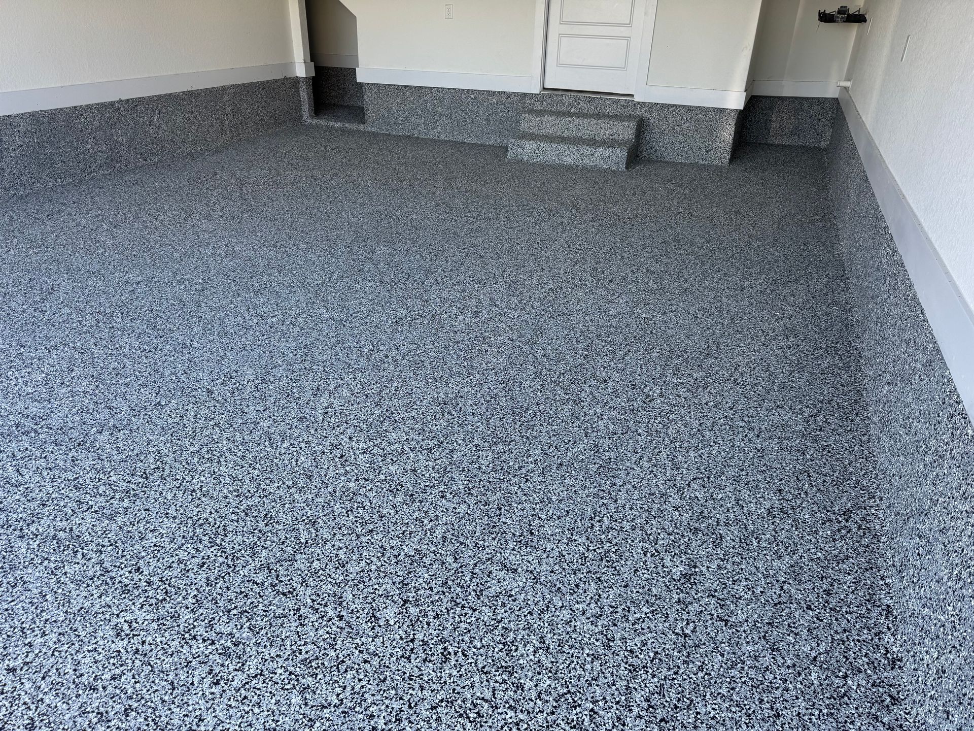 Empty speckled gray carpeted room with white walls and built-in cabinets at the back