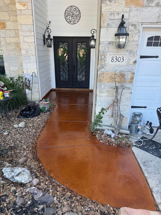Front porch with black double doors, white stone walls, lanterns, and a curved copper-colored walkway