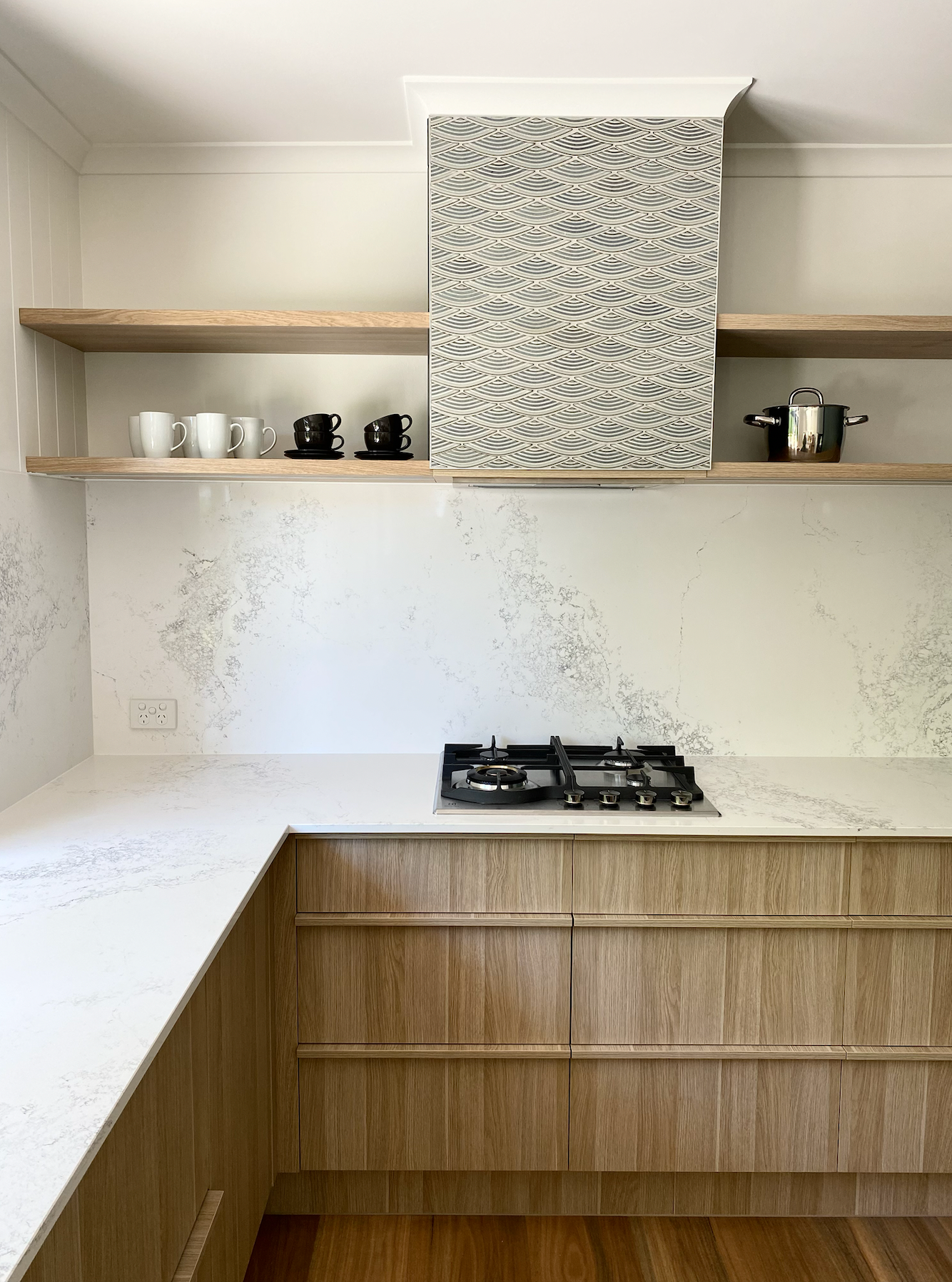 Modern kitchen with light wood cabinets, white stone countertops, open shelves, and a patterned range hood. — Foreshore Kitchens in Coolum Beach, QLD