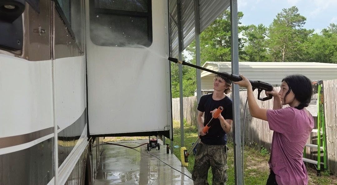 People cleaning the RV in the garage