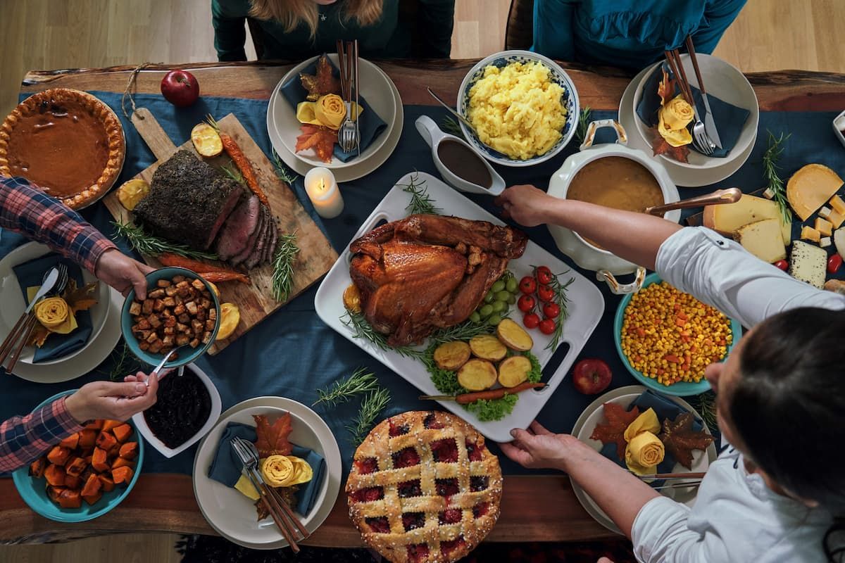 A group of people are sitting at a table eating a thanksgiving dinner.