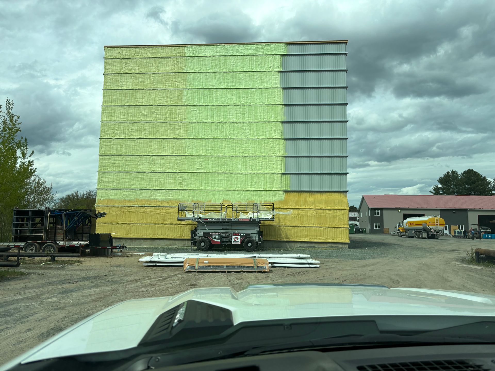 Bâtiment en construction ; murs extérieurs recouverts d'isolant et partiellement de bardage métallique.