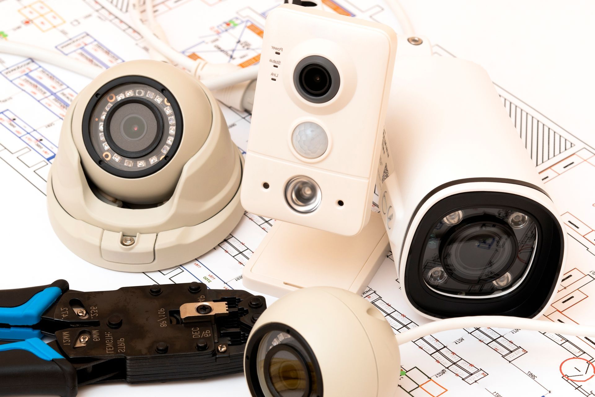 Assorted security cameras and wiring tools on a floor plan