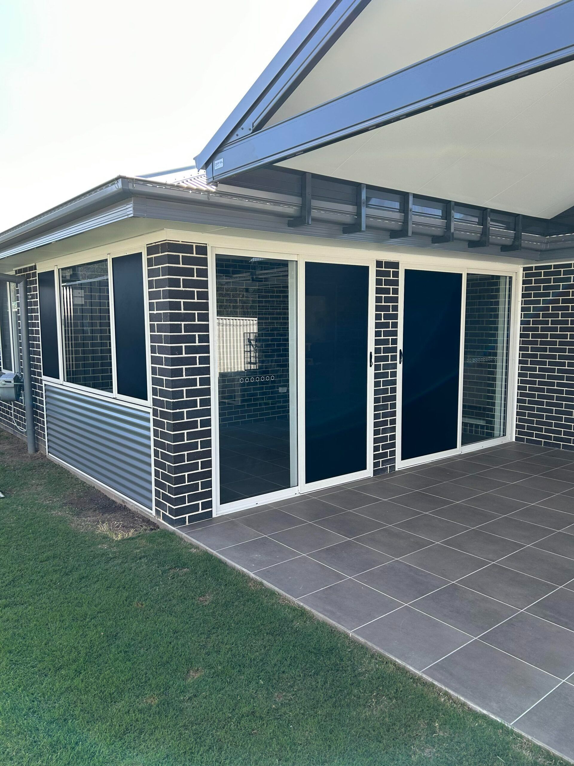Outdoor patio with gray tile floor, dark blue tinted windows — Envy Glass in Nambucca Heads, NSW