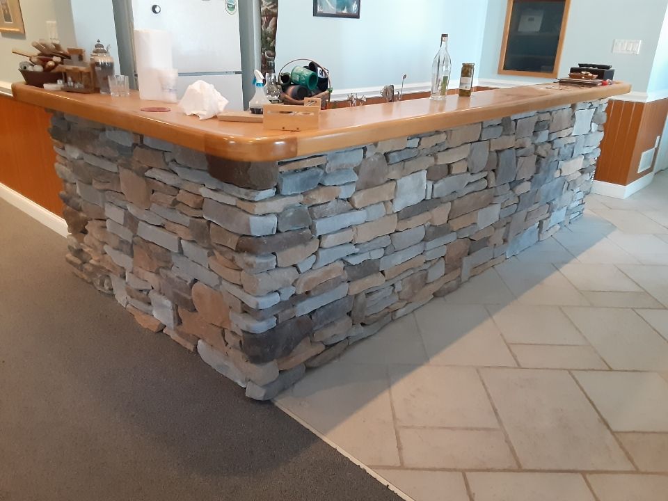 Stone-faced reception counter with wooden top in a tiled lobby area